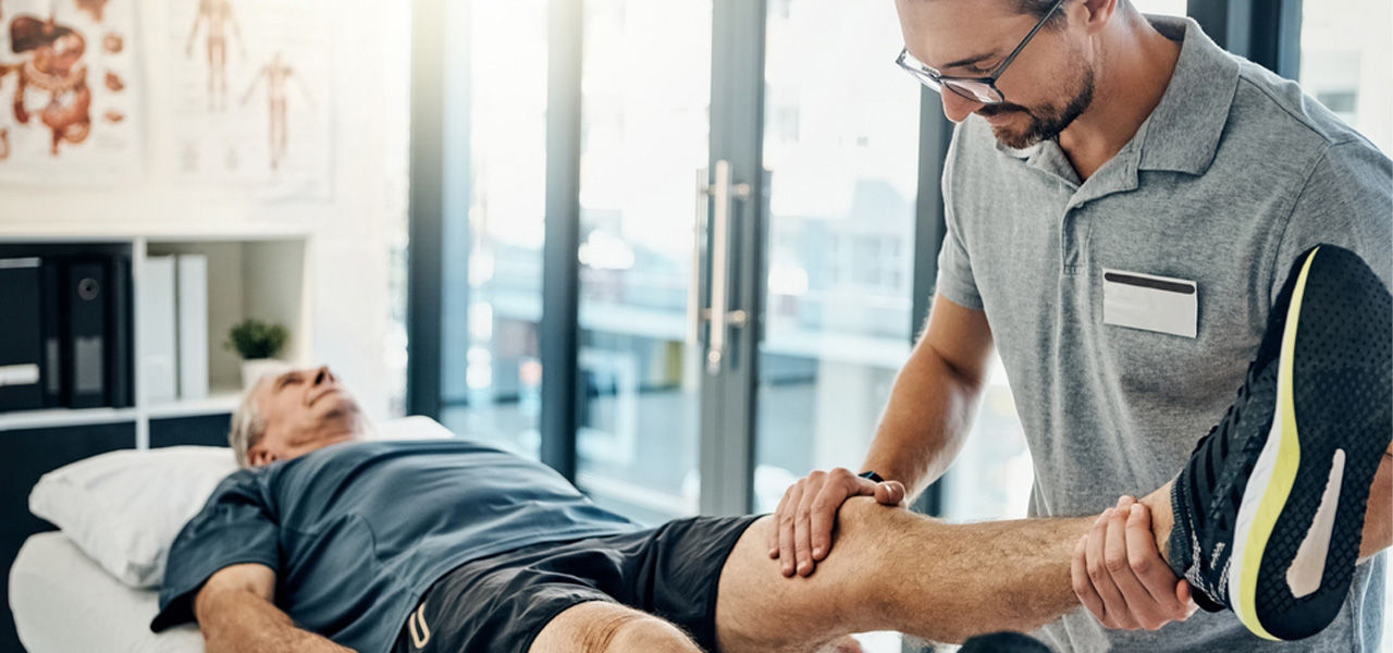 physical therapist working with senior patient leg